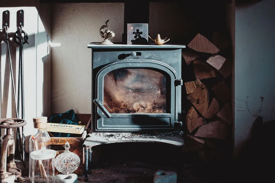 Aged vintage fireplace placed on table in rustic house near pile of firewood on sunny day